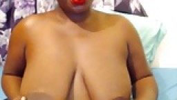 Tashay: cette black place un gode entre ses gros seins et le suce face à la webcam hd